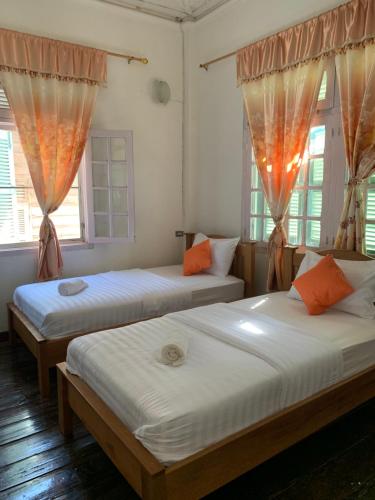 two beds in a room with two windows at The White House in Chiang Khan
