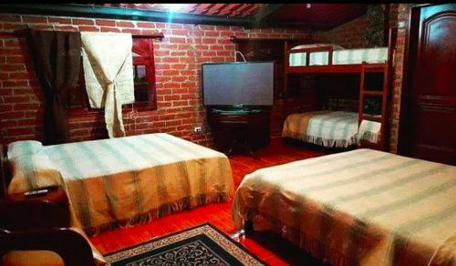 a bedroom with two bunk beds and a television at Rancho los Emilios in Alausí