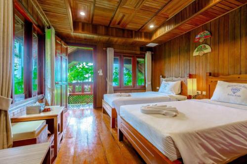 two beds in a room with wooden walls and windows at Diamond Beach Resort in Ao Nam Mao
