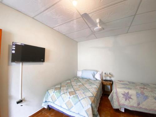 a bedroom with a bed and a flat screen tv at MARIA III HOSTAL in Juayúa