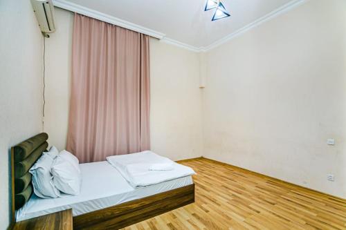 een kamer met een bed met een gordijn en een houten vloer bij Квартира у Театра Р. Бейбутова. in Baku