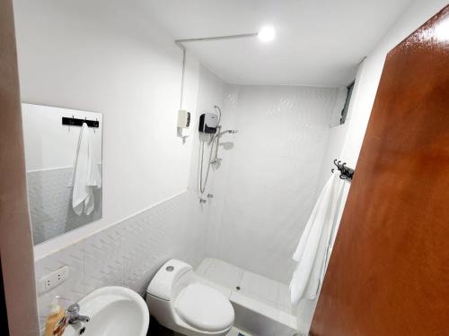 a white bathroom with a toilet and a sink at Acogedor departamento en Huacachina in Ica