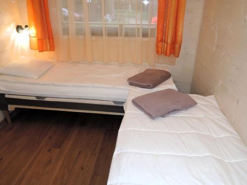 two beds in a small room with a window at Nowe domki wakacyjne blisko morza W Dziwnówku in Dziwnówek