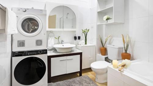 a white bathroom with a washing machine and a sink at Fern Creek Cottage in Berrima