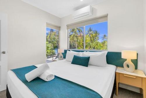 a bedroom with a large white bed with a window at Sarayi Boutique Hotel in Palm Cove
