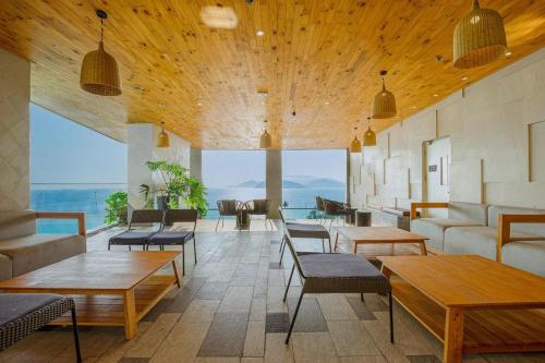 eine Lobby mit Tischen und Stühlen und einem großen Fenster in der Unterkunft Panorama Sky Blue Nha Trang in Nha Trang