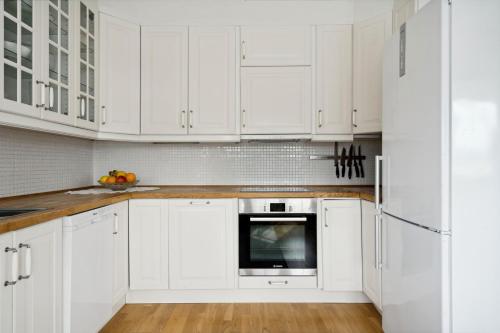 - une cuisine blanche avec parquet et placards blancs dans l'établissement Idyllisk hus ved sjøen, à Hammerfest