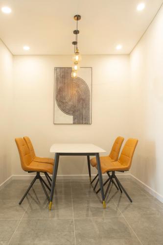 a table and chairs in a room with a picture at TSQ STAY Hotel Apartment in Hanoi