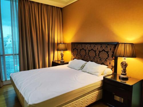 una camera da letto con un letto con due lampade e una finestra di Apartement The Peak Sudirman a Giacarta