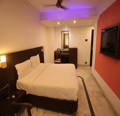 a bedroom with a white bed and a television at DFRONT GOLDEN PALACE in Nāmakkal