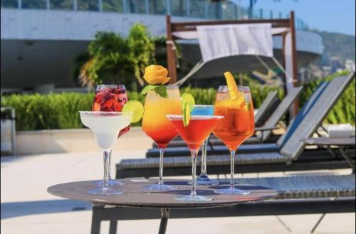 four drinks on a tray on a table near a pool at Hotel Nacional Rio de Janeiro in Rio de Janeiro