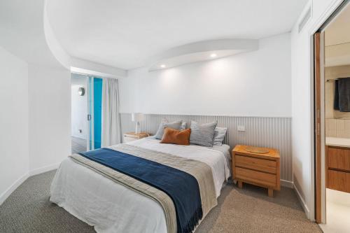 Dormitorio blanco con cama y mesa de madera en Sirocco 404 luxurious 3 bedroom unit, ocean front, en Mooloolaba
