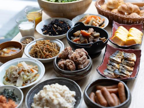 APA Hotel Hatchobori Ekimae في طوكيو: طاولة مليئة بالأطباق بأنواع مختلفة من الطعام