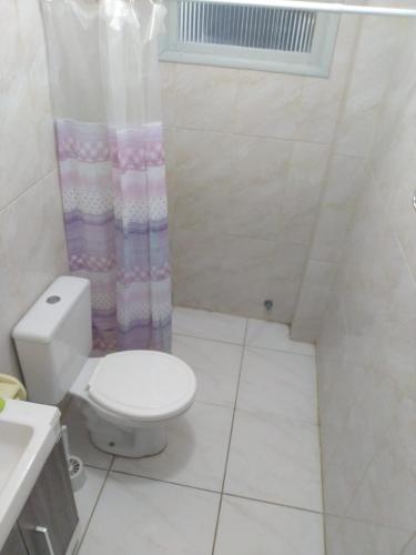 a bathroom with a toilet and a shower curtain at AP beira mar perto do centro in Capão da Canoa