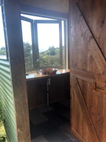 a bathroom with a sink and a window and a door at Sunrise Cabin at First Light Rangihaeata Retreat in Takaka