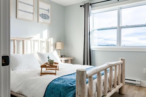 a bedroom with a white bed with a table on it at New English Point Oceanfront Living With Hot Tub in Head of Jeddore