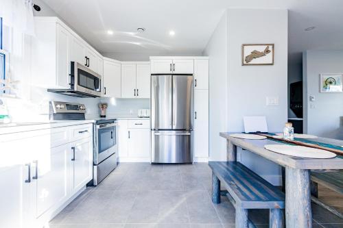 a kitchen with white cabinets and a stainless steel refrigerator at New English Point Oceanfront Living With Hot Tub in Head of Jeddore