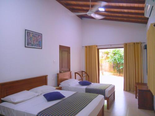 1 dormitorio con 2 camas y ventana grande en Volunteer Ceylon en Ratnapura