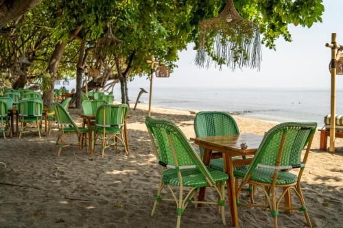 a group of chairs and tables on the beach at Taman Sari Bali Resort and Spa in Pemuteran