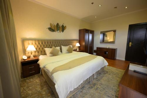 a bedroom with a large bed with two lamps and a desk at رمال الجزيره in Al Ḩawīyah