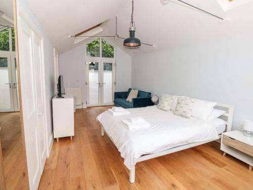 um quarto branco com uma cama e uma cadeira azul em Bay Tree Cottage, Dartmouth em Dartmouth