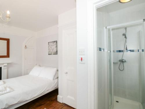 a white bedroom with a shower and a bed at Bay Tree Cottage, Dartmouth in Dartmouth