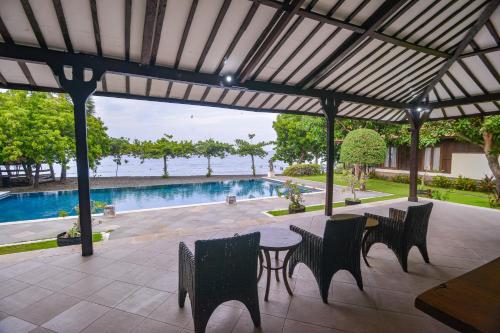 a patio with a table and chairs and a pool at The Joglo By The Beach Pemuteran Bali in Pemuteran