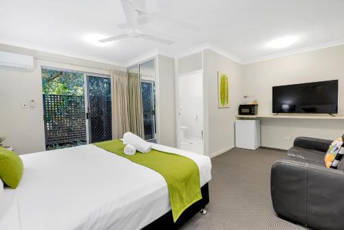 a bedroom with a bed and a tv and a couch at Sarayi Boutique Hotel in Palm Cove