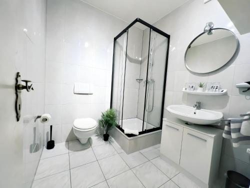 uma casa de banho branca com um chuveiro, um WC e um lavatório. em Apartment Hotel Lindeneck em Erfurt