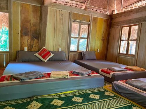 two beds in a room with wooden walls and windows at LePont Mu Waterfall Bungalow in Hòa Bình