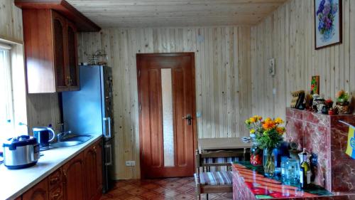a kitchen with a refrigerator and a table with flowers at Cottage Ozerniy in Lazeshchyna