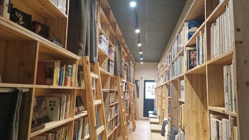 a library with wooden shelves filled with books at Hsinchu Book&Bed in Hsinchu City