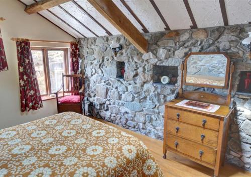a bedroom with a stone wall with a bed and a dresser at The Granary in Caernarfon