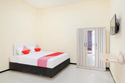 a white bedroom with a bed with red pillows at SUPER OYO 1468 SM House in Malang