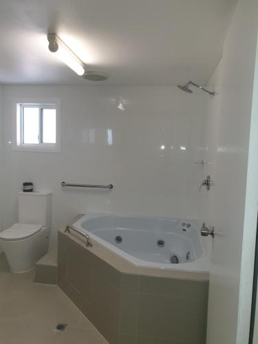 a white bathroom with a tub and a toilet at Forstay Motel in Forster
