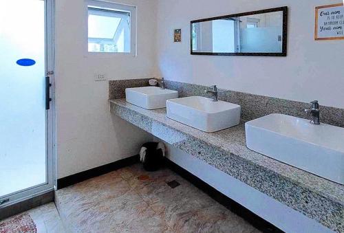 a bathroom with two white sinks and a mirror at RedDoorz @ Recson Hostel Coron Palawan in Coron