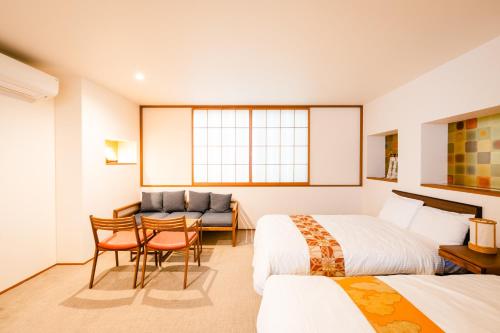 a hotel room with two beds and a table and chairs at Hotel Rakurakuan in Kyoto