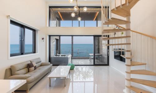 a living room with a couch and a staircase at Dal Bodre Pool & Spa Pension in Pohang