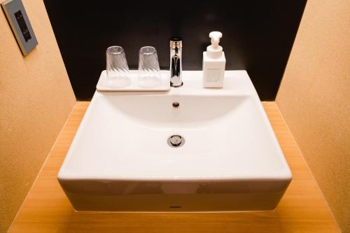 a white bathroom sink with a soap dispenser on it at Hotel Rakurakuan in Kyoto