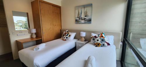 two beds in a room with white sheets at Phillip Island Apartments in Cowes