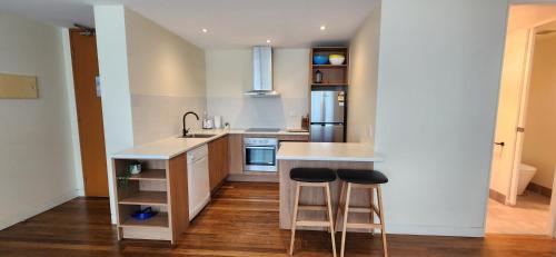 a kitchen with a counter and two stools in it at Phillip Island Apartments in Cowes