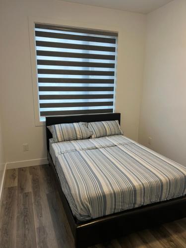 a bed in a room with a large window at Panel Apartment in Winnipeg