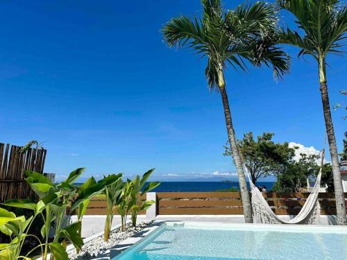 a swimming pool with two palm trees and a hammock at Pawikan Seaview Villa in Moalboal
