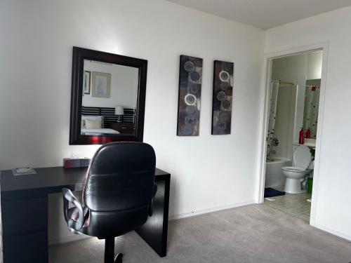una oficina con una silla negra y un espejo en Hidden valley treehouse home! en Calgary
