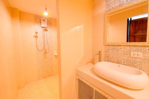 uma casa de banho com um lavatório e um chuveiro em เเองเจล่า รีสอร์ท em Pran Buri