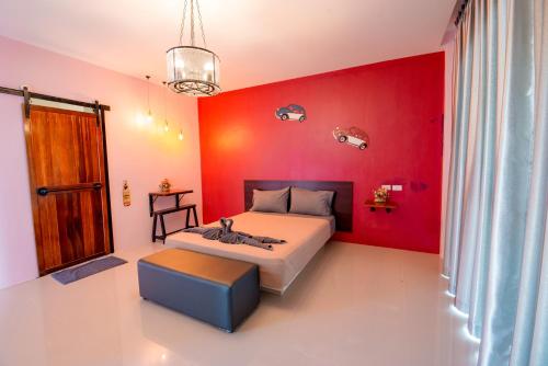a bedroom with red walls and a bed and a stool at เเองเจล่า รีสอร์ท in Pran Buri