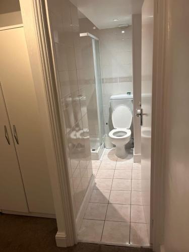 a bathroom with a toilet and a glass shower at SouthStreet Suites in Isleworth