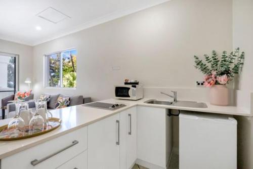 a white kitchen with a sink and a microwave at Sarayi Boutique Hotel in Palm Cove
