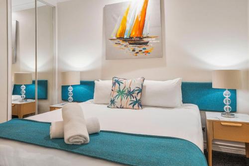 a bedroom with a large white bed with blue accents at Sarayi Boutique Hotel in Palm Cove