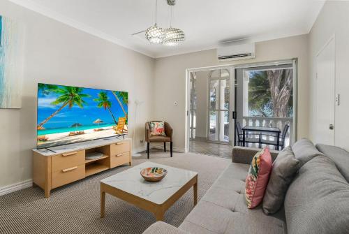 sala de estar con sofá y TV de pantalla plana en Sarayi Boutique Hotel, en Palm Cove